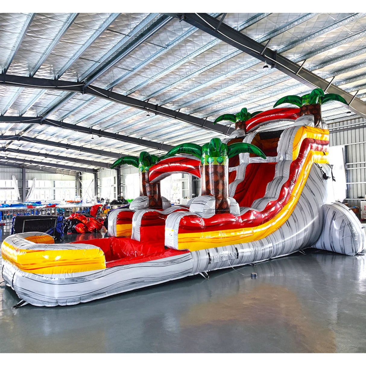 15ft Fire Island Commercial Single Lane Inflatable Water Slide angled view highlighting red slide, yellow inflatable pool, palm trees, and tropical theme in a warehouse environment
