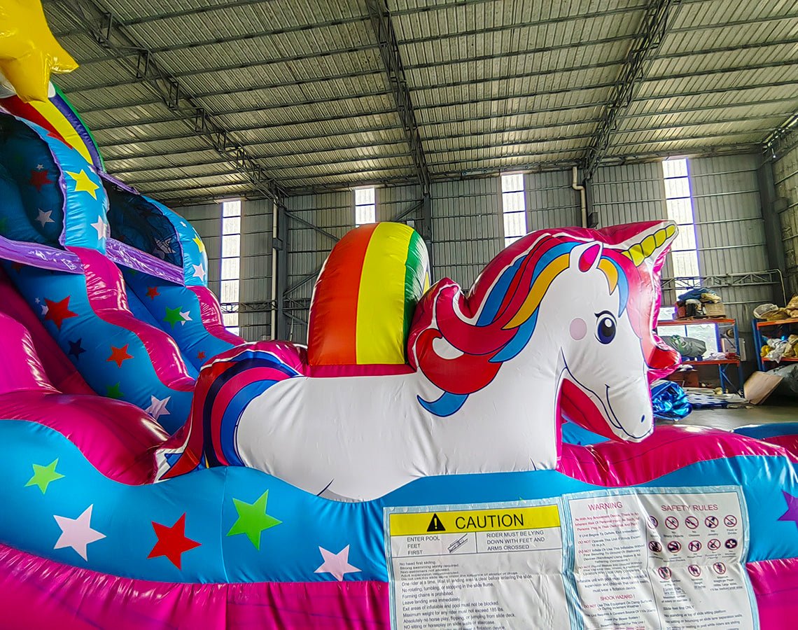 Detail of Unicorn Splash water slide featuring large inflatable unicorn figure, colorful star decorations, and safety instructions placard.