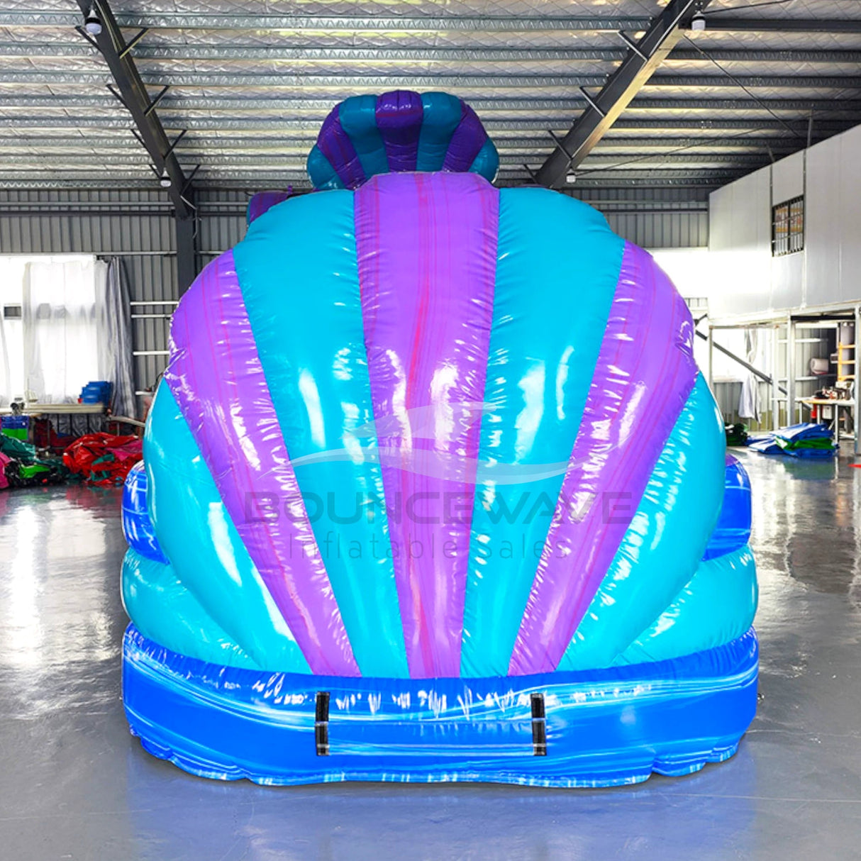 Front view of Mermaid's Cove inflatable water slide displaying vibrant blue and purple design with shell-shaped top and large splash area.