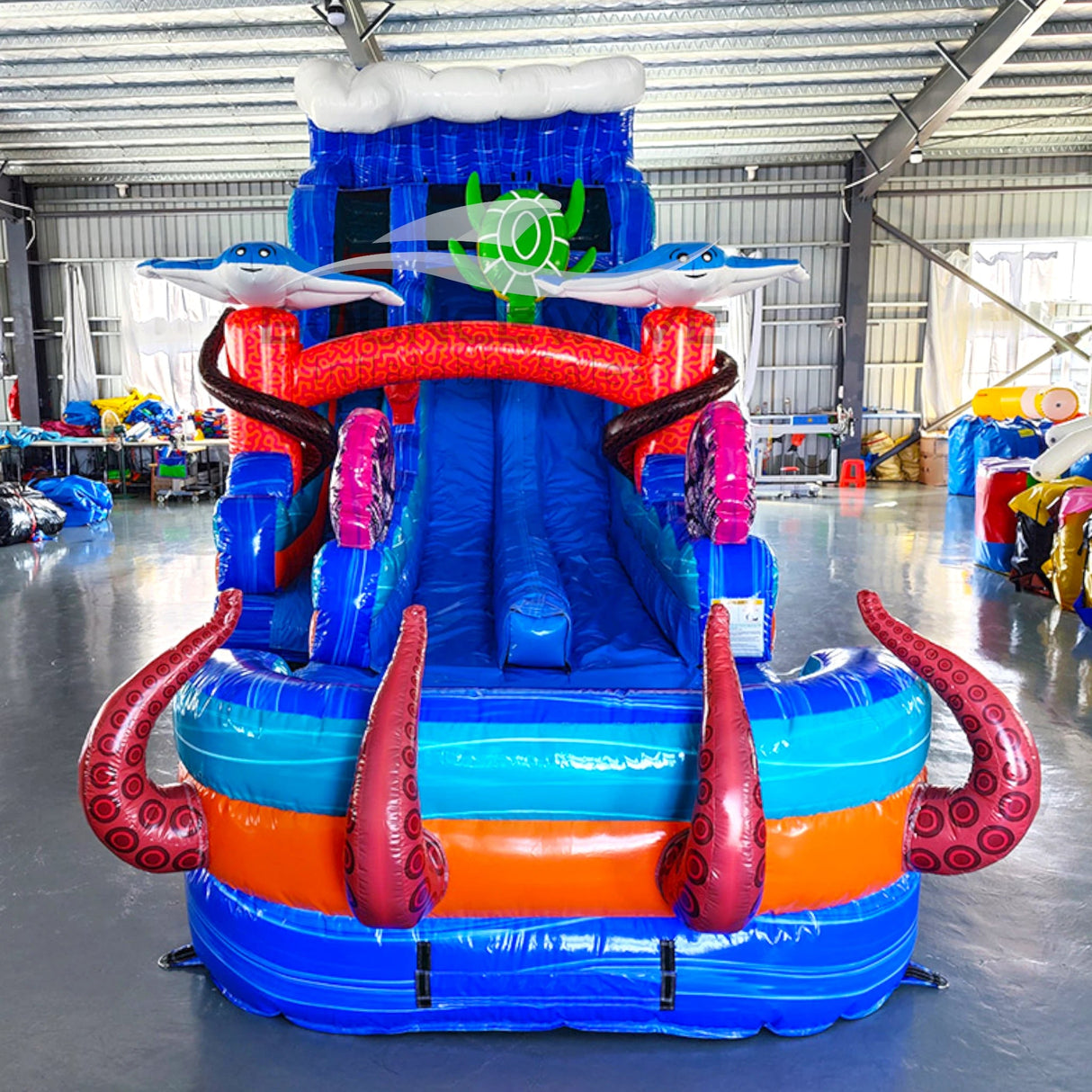 Front view of Reef Racer hybrid water slide in indoor setting, showing tall structure with dual sliding lanes, shark figures, and colorful sea-life decorations.