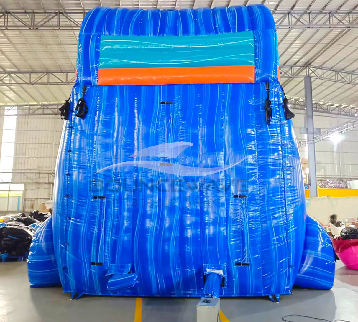 Rear view of 20ft Hammerhead Reef Hybrid DL water slide showing blue color scheme, inflatable shark figures on top, and enclosed tube slide sections. The slide is set up in an indoor facility with white walls and metal roofing visible.