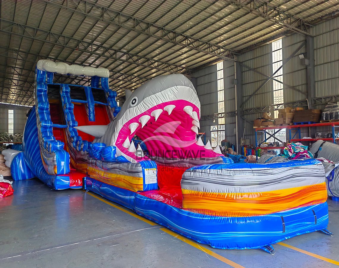 20ft Rip Curl Shark Attack 2pc Hybrid Dual Lane Inflatable Water Slide side view displaying shark head, blue water slide, and multicolored inflatable pool area