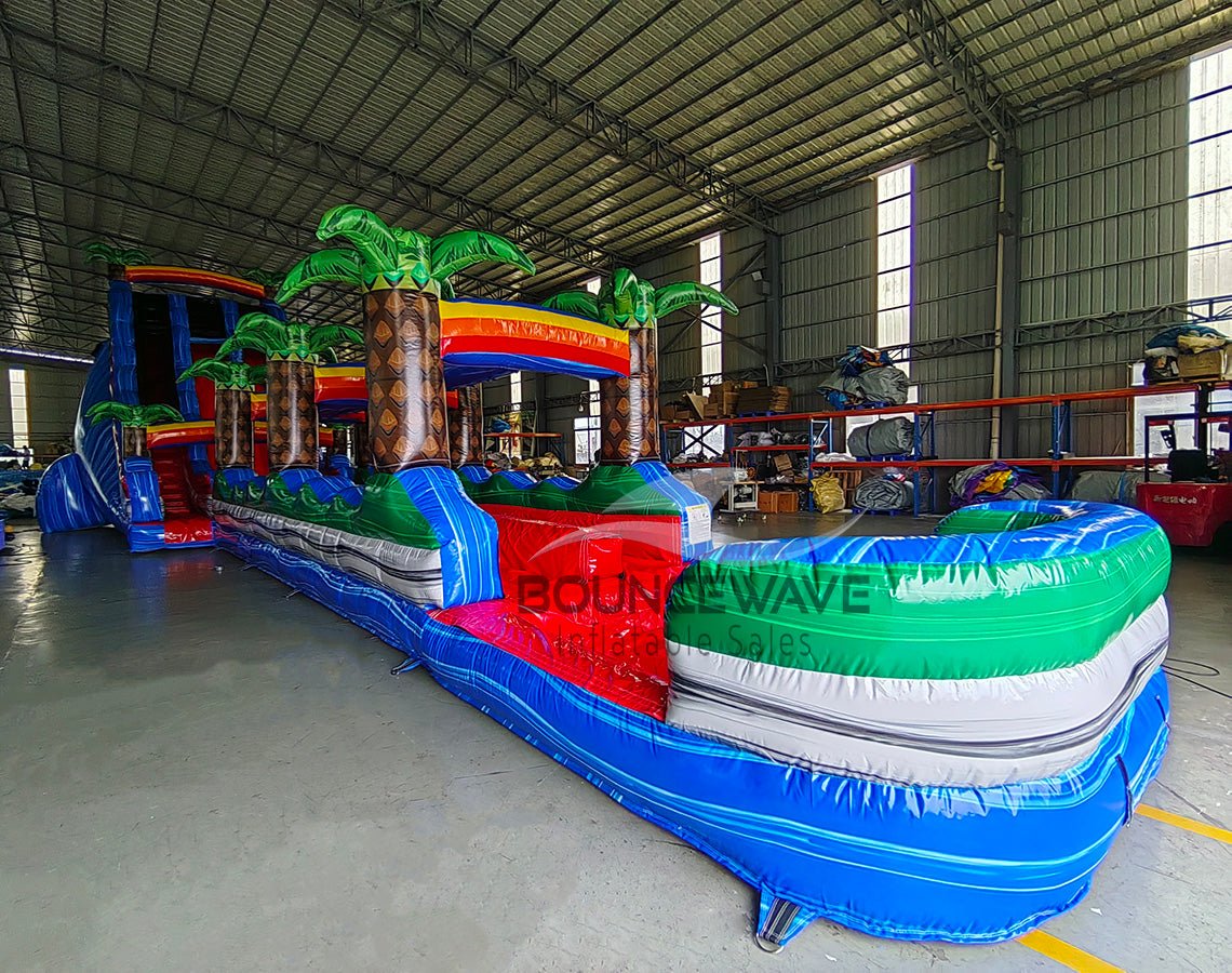 24ft Baja Splash DL 2pc Commercial Water Slide with Inflatable Slip & Slide side angle view highlighting curved slide, tropical theme, and extended water play area
