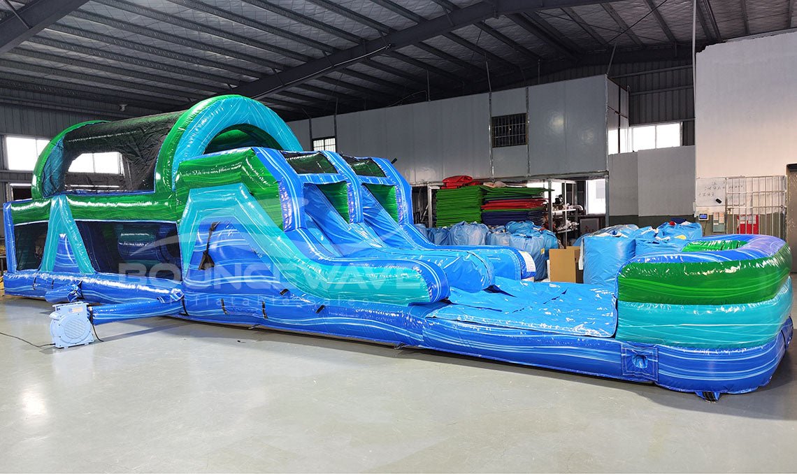 46ft Island Drop Hybrid Inflatable Obstacle Course full length view highlighting blue and green structure, various obstacles, and water slide ending in pool area