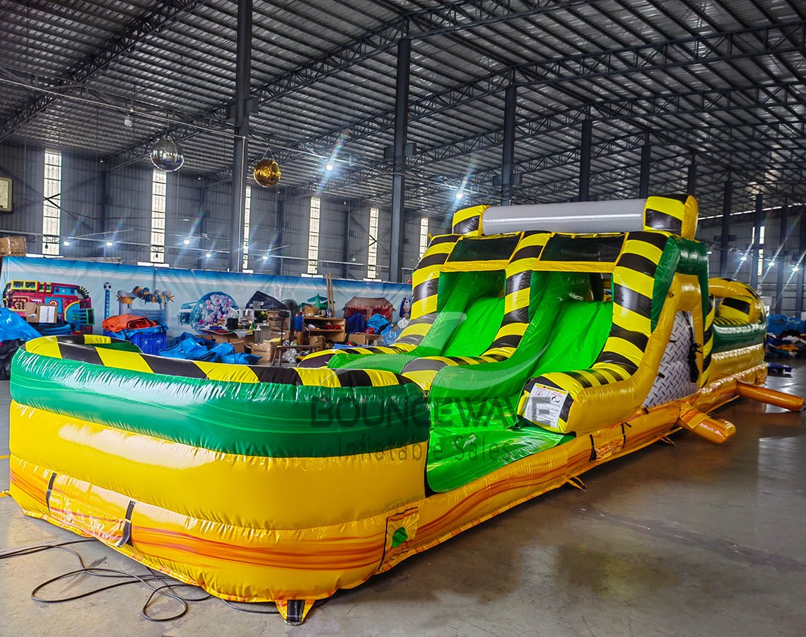 46ft Toxic Open Air Hybrid Inflatable Obstacle Course featuring yellow and black hazard stripes, multiple arches, and green base in large warehouse setting