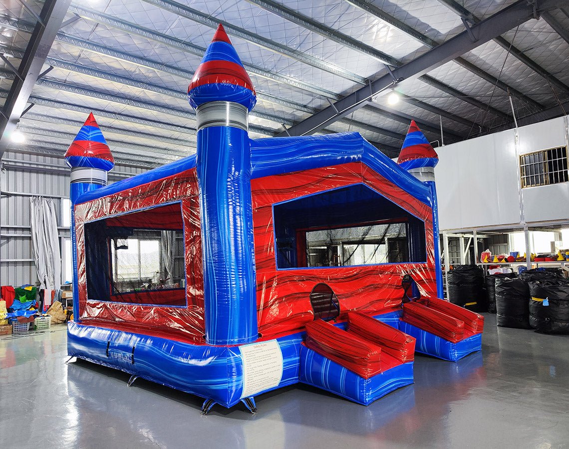 Baja XL Commercial Grade Bounce House with red and blue castle design featuring three turrets and dual entrance slides in warehouse setting
