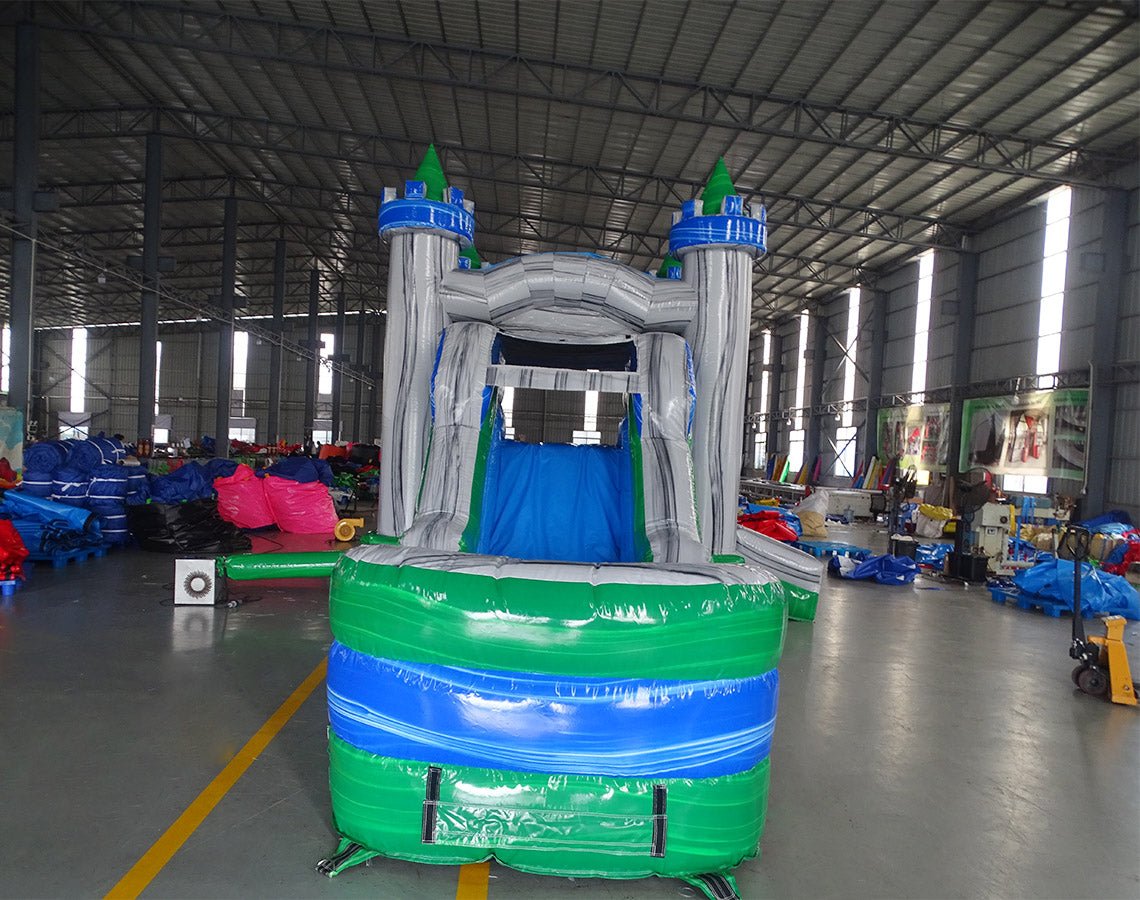 Front view of Euro Green Gush Commercial Econo Inflatable Wet/Dry Combo, showcasing the bounce house entrance with blue and silver walls, green turrets, and colorful interior. Features a green slide and splash pool area. Set up in an indoor warehouse with metal roofing visible.