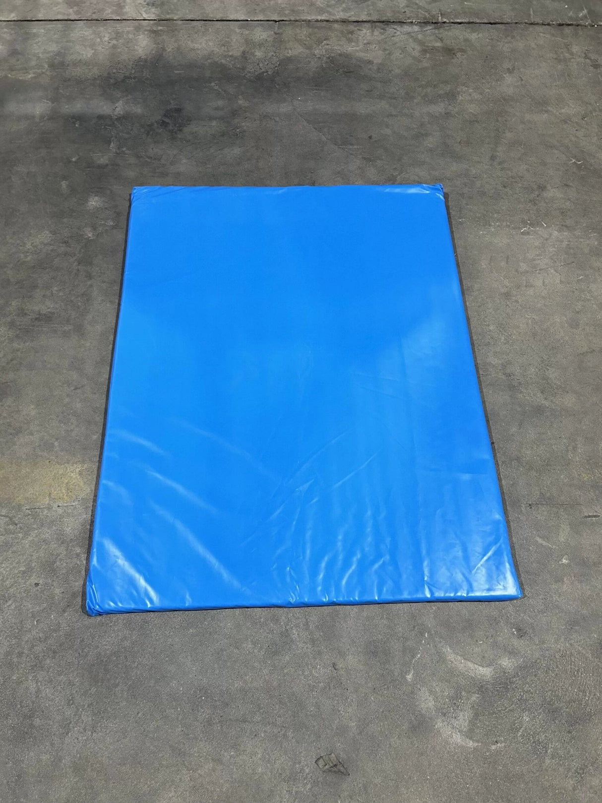 Impact Safety Mat for Inflatables showcasing rectangular blue cushioned mat with reinforced borders on gray concrete surface