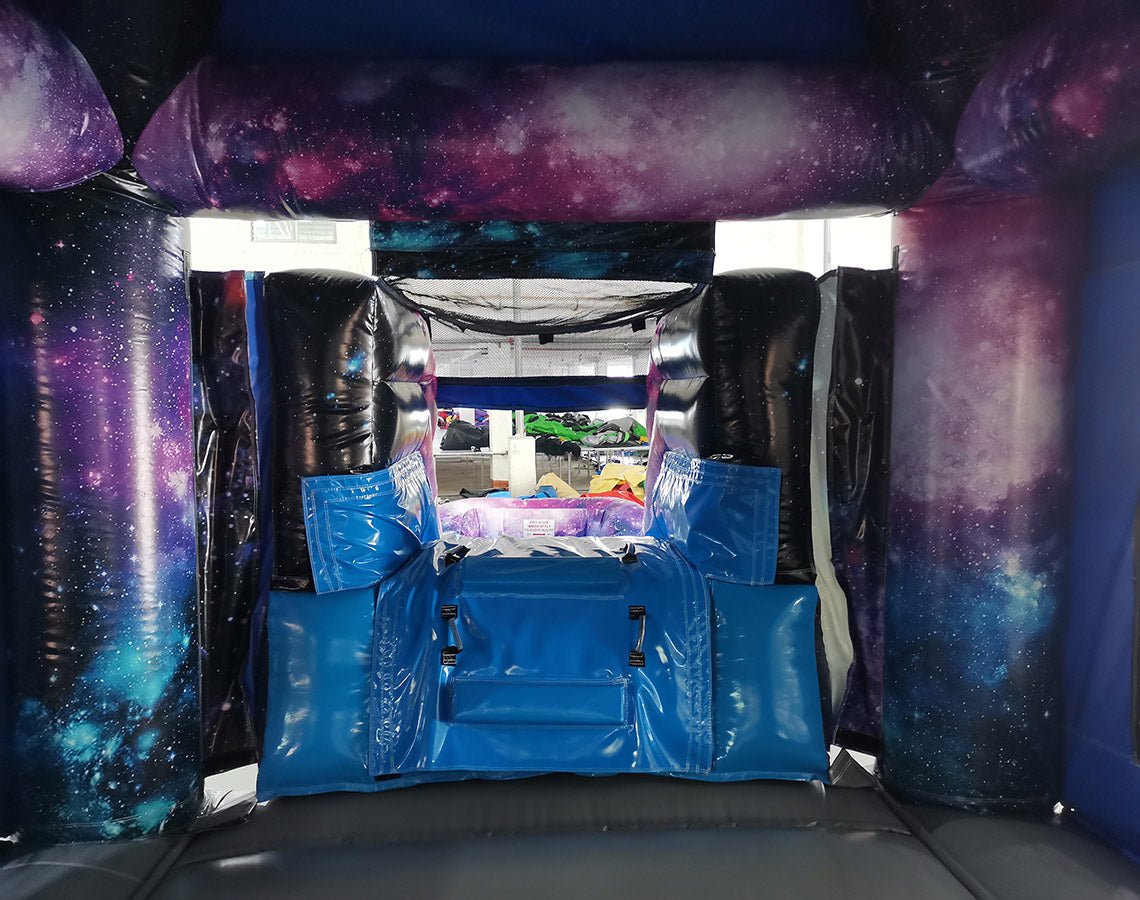 Wide-angle view of MoonWalker Commercial Econo Inflatable Wet/Dry Combo featuring a space-themed bounce house with cosmic design, attached slide, and play area. The inflatable has bright purple, blue, and pink colors with astronaut and rocket decorations. Displayed against a white background, showcasing its full design and features.