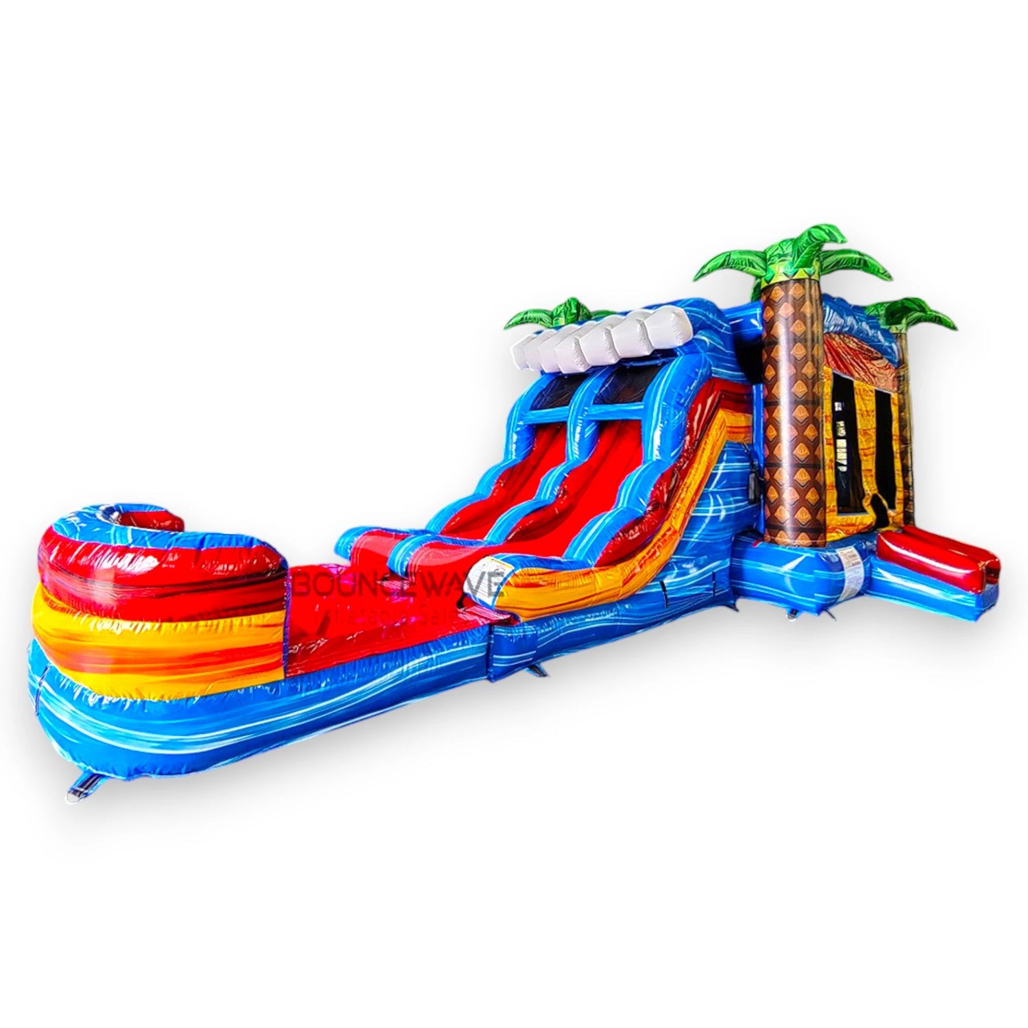 Close-up view of Rip Curl Dual Lane Commercial Inflatable Combo (Wet/Dry) isolated on a white background. The inflatable showcases dual blue slides, brown palm tree trunks with blue leaves, a yellow and blue bounce house structure, and a large circular splash pool with vibrant rainbow-colored rings. The design highlights its tropical theme for commercial use.