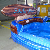 Inflatable blue and brown "South Beach" water slide with single lane and curved design, set up in an indoor warehouse space