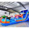 Side view of Hammerhead Reef hybrid water slide in warehouse, showcasing its length, dual blue lanes, shark decorations, and large splash area with octopus tentacles.