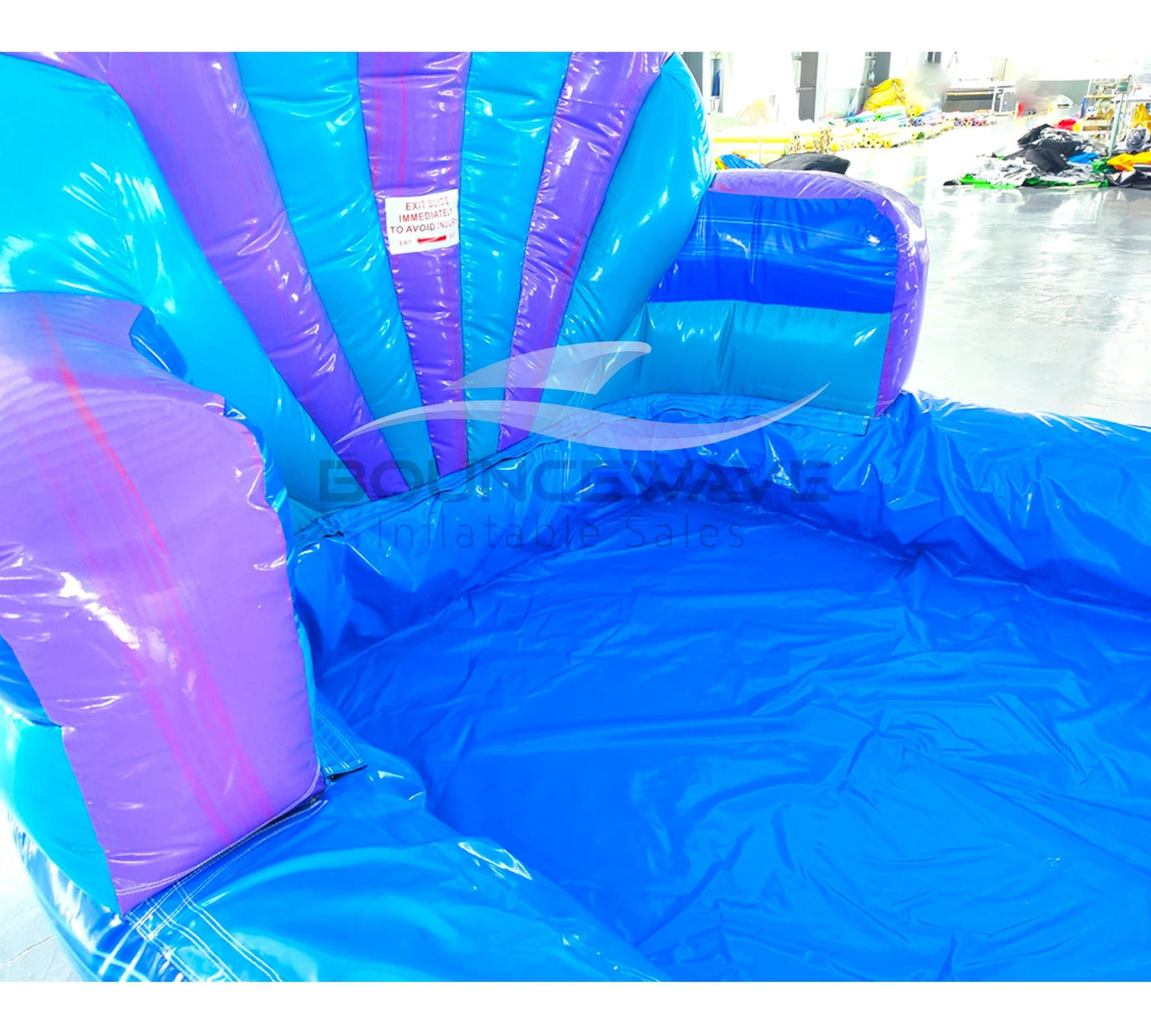 close-up view of Mermaid's Cove inflatable water slide displaying vibrant blue and purple design with shell-shaped top and large splash area.
