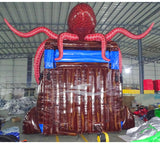 Large inflatable water slide featuring a giant red octopus design with tentacles, dual sliding lanes, and a brown ship-like base in an indoor warehouse setting.