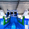 Large inflatable water slide with ocean theme, featuring blue sliding lanes, dolphin decorations, and a spacious splash pool area. The slide combines open and enclosed sections, set up in an indoor warehouse with metal roofing visible.