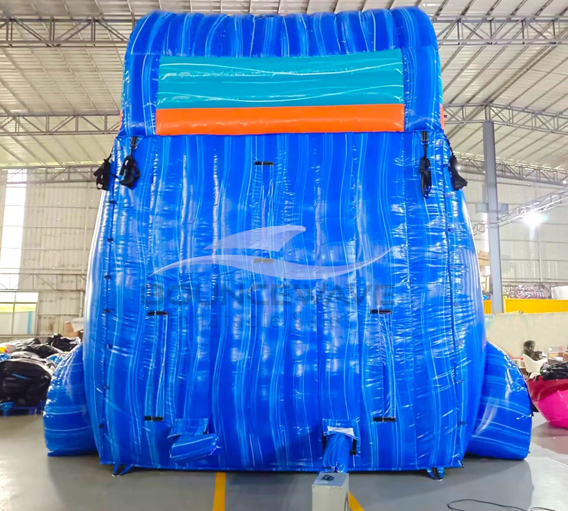 Rear view of 20ft Hammerhead Reef Hybrid DL water slide showing blue color scheme, inflatable shark figures on top, and enclosed tube slide sections. The slide is set up in an indoor facility with white walls and metal roofing visible.