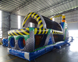 cross rear view of 53ft XL Radioactive Run Commercial Hybrid Inflatable Obstacle Course showing inflatable obstacles. The image displays yellow and gray cylindrical barriers, green flooring, and yellow and black striped walls. Various inflatable obstacles are visible, including tunnels and climbing areas, demonstrating the course's challenging layout.
