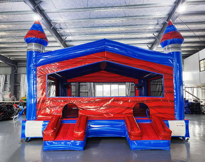 Baja XL Commercial Grade Bounce House displaying red walls, blue trim, three pointed turrets, and large mesh windows in indoor facility
