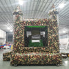 Front view of Camo Econo Combo, showcasing the bounce house entrance with camouflage design, mesh windows, and two pointed turrets. The combo includes a slide and splash pool area. Displayed in an indoor facility with other inflatable products visible.