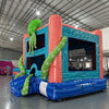 Close-up view of the bounce house entrance of Deep Sea Dive Dual Lane Commercial Inflatable Combo. Shows the blue wave-patterned base, green tentacles with eyes, and part of the orange octopus. The bounce house area is visible with mesh windows and a coral-patterned interior. Set in a warehouse with concrete flooring and other inflatable products in the background, showcasing its commercial use.
