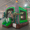 Dino Dive Commercial Grade Bounce House side view displaying lifelike T-Rex, grey castle walls, and green tropical elements
