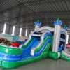 Side view of Euro Green Gush Commercial Econo Inflatable Wet/Dry Combo showing blue and silver castle structure with green turrets, slide, and splash pool. Set up in a spacious indoor warehouse with other inflatable products and equipment visible in the background.