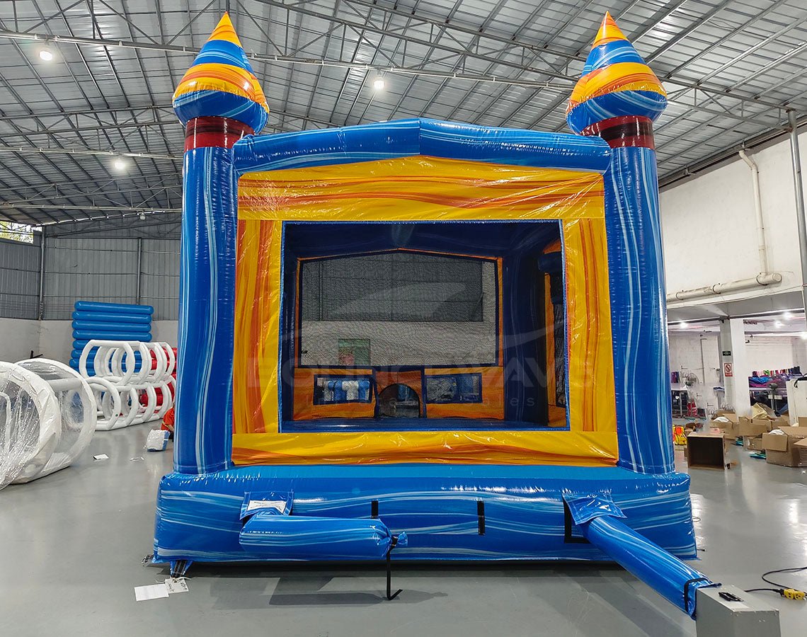 Fire and Ice Commercial Grade Bounce House interior view with yellow walls, mesh windows, and blue floor in warehouse environment
