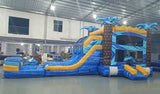 Flashpoint Dual Lane Commercial Inflatable Combo (Wet/Dry) showcasing blue and yellow design with palm tree pillars, dual slides, and large splash area in warehouse setting
