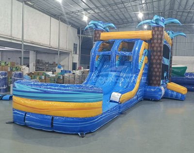 Flashpoint Dual Lane Commercial Inflatable Combo (Wet/Dry) side view highlighting dual blue slides, yellow accents, inflatable palm trees, and extended splash pool in indoor facility