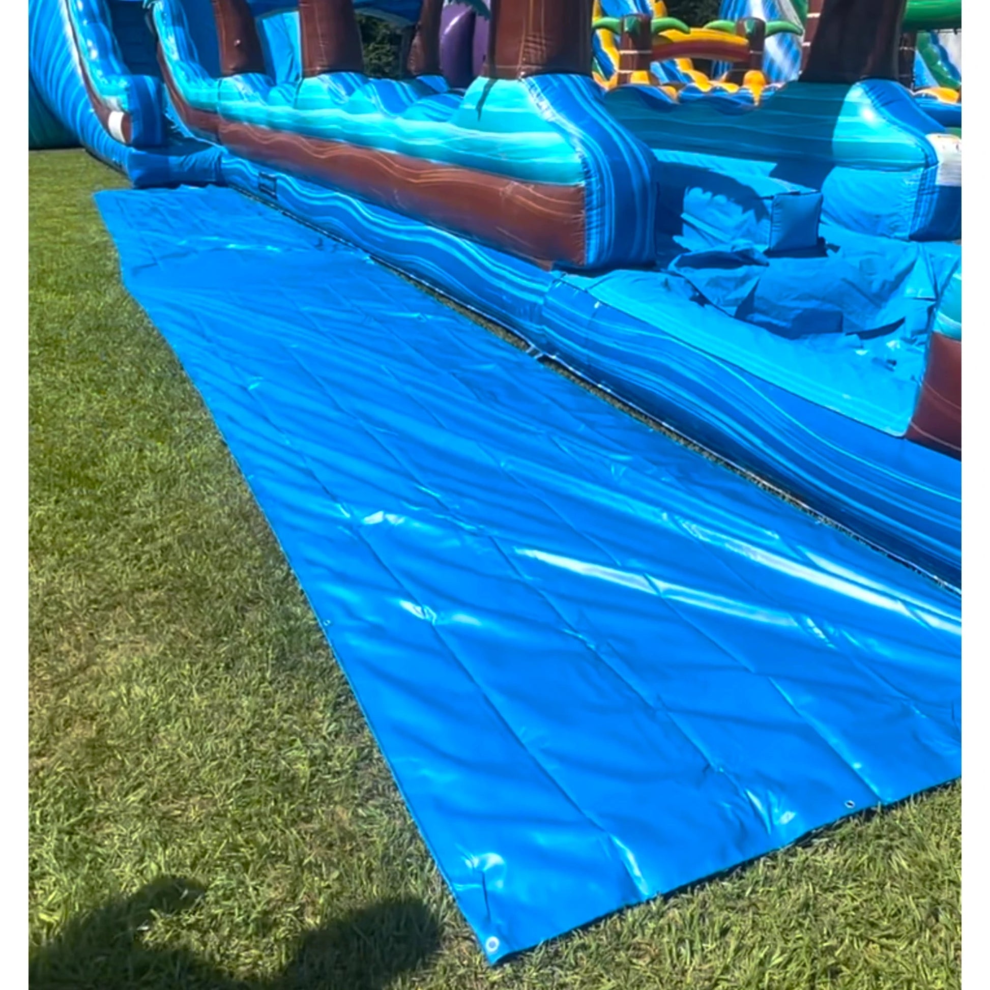 Heavy Duty Tarp for Inflatable Hybrid Water Slide featuring blue waterproof material, reinforced edges, and metal grommets for secure attachment on grass surface
