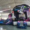 Side view of MoonWalker Commercial Econo Inflatable Wet/Dry Combo showing space-themed inflatable with cosmic patterns, slide, and play area. Features vibrant purple, blue, and pink colors with astronaut and rocket designs. Set up in a spacious indoor warehouse.