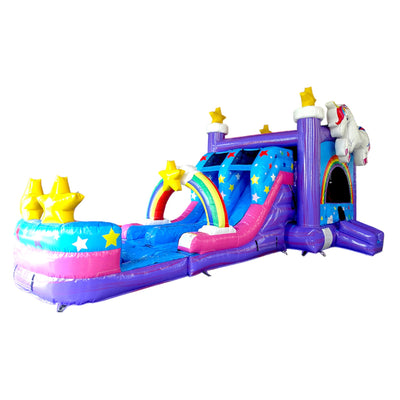 Large inflatable unicorn-themed combo featuring a bounce house with rainbow arch entrance, star decorations, attached slide, and play area. The structure has vibrant purple, blue, pink, and yellow colors with an inflatable unicorn figure on top. Set up against a white background, showcasing its whimsical design and multiple play elements.